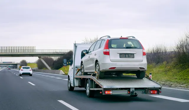 Carro attrezzi che trasporta un'auto da rottamare in autostrada